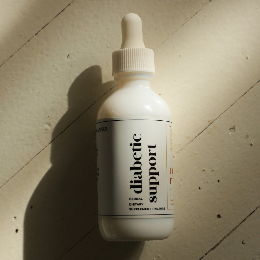 White tincture droplet bottle with a minimal white label with black lower-case serif text saying "diabetic support." The bottle sits on a light wooden background with a drop shadow going to the bottom left.